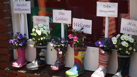 flowers planted in galoshes with Welcome written in 6 languages