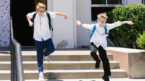 two school boys leaping joyously down the stairs out of school in the sunshine