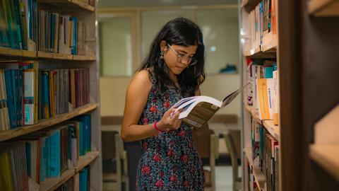 woman reading among library stacks