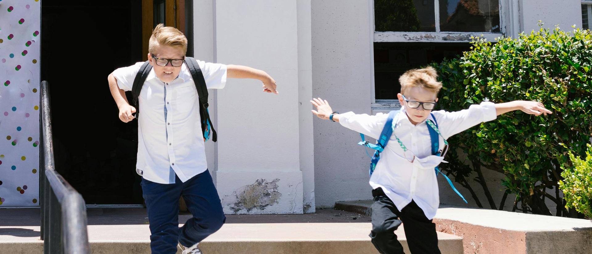 two school boys leaping joyously down the stairs out of school in the sunshine