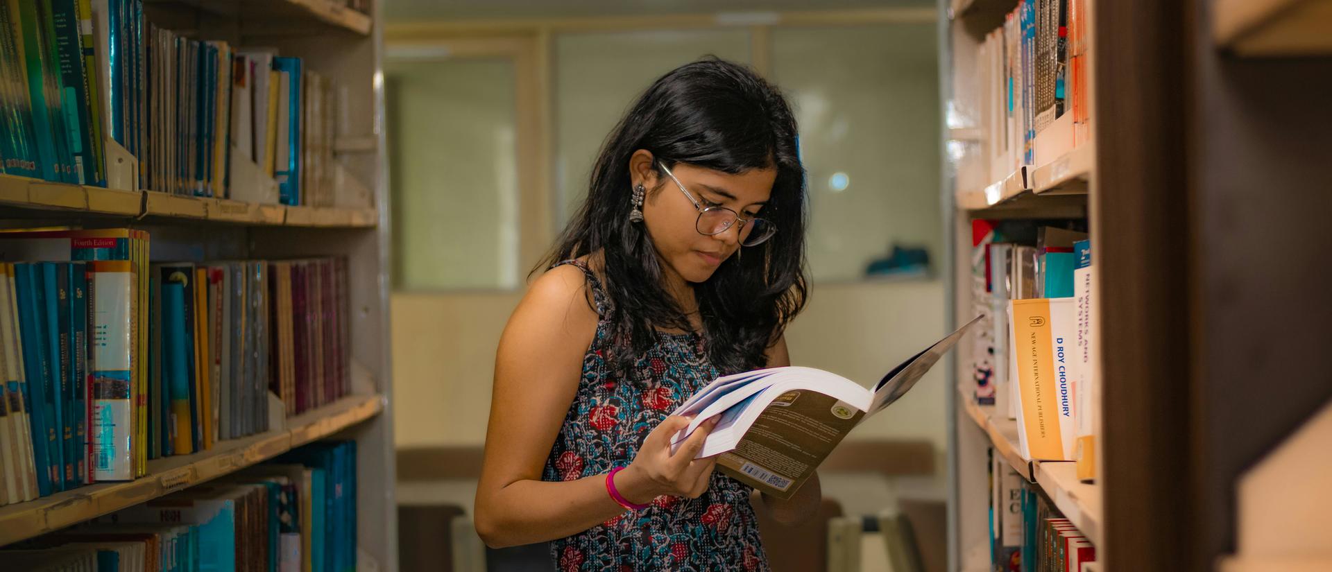 woman reading among library stacks